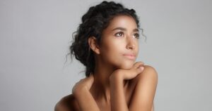 happy-serene-young-woman-with-beautiful-olive-skin-curly-hair-ideal-skin-brown-eyes-studio-min